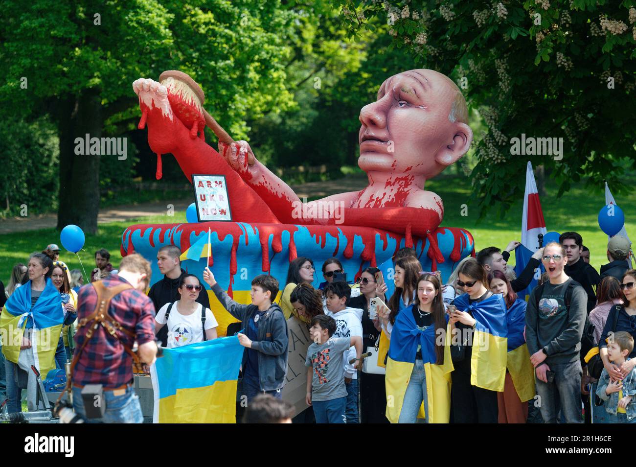 Aachen, Germany. 14th May, 2023. Participants of a demonstration against protests against arms deliveries to Ukraine stand in front of a carnival figure of Russian President Putin in a bloodbath from the Rosenmontagszug in Düsseldorf. Ukrainian President Selenskyj is in Germany for the first time after the start of the Russian war of aggression. On Sunday afternoon, Selenskyj and the Ukrainian people are to be honored in Aachen with the Charlemagne Prize for services to the unity of Europe. Credit: Henning Kaiser/dpa/Alamy Live News Stock Photo