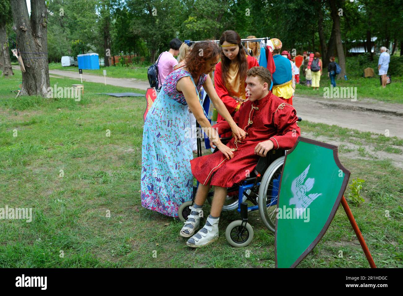 Women helping the man with special needs to sit down in a wheelchair ...