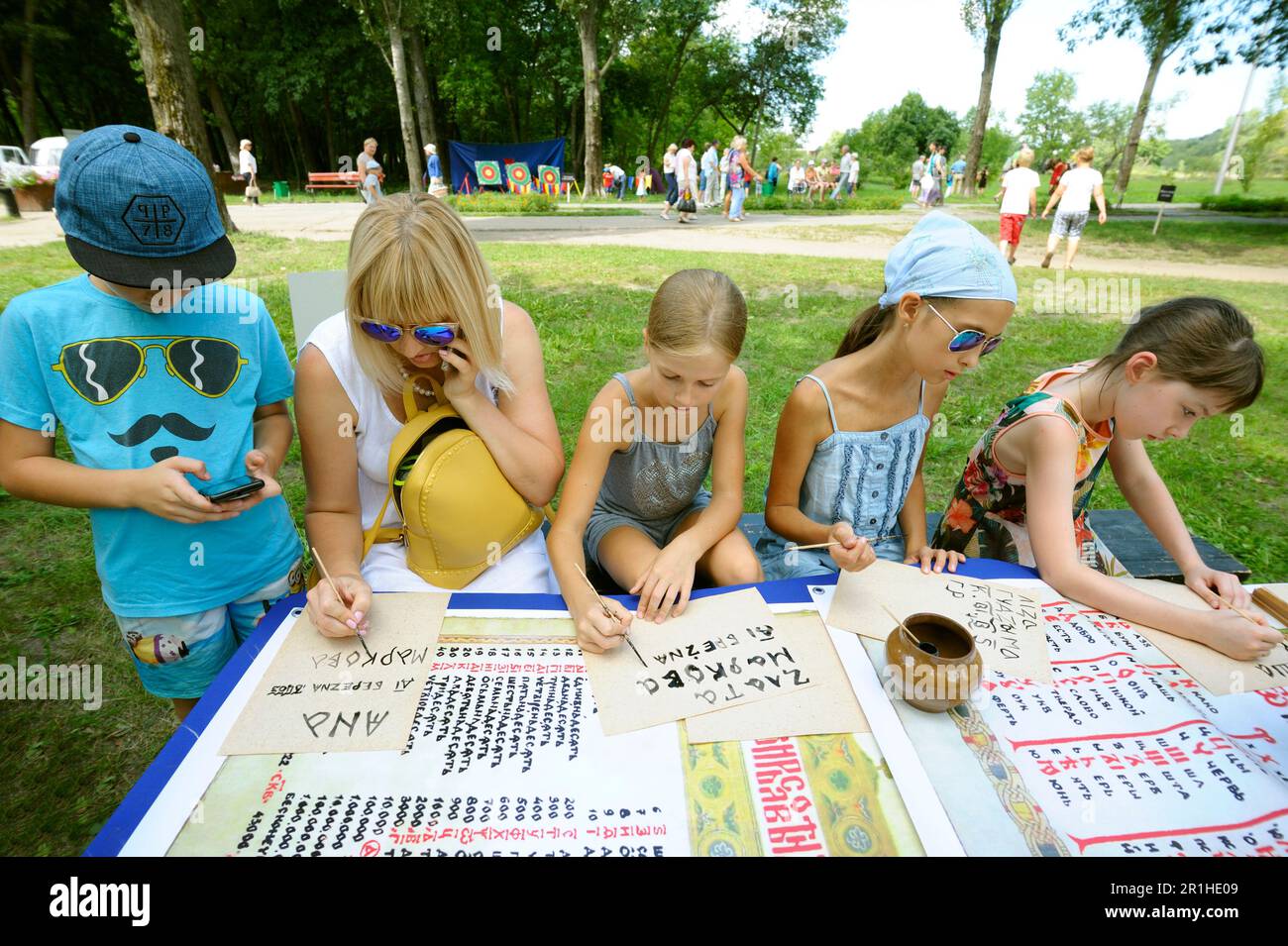 Young woman and four kids writing in papers learning ancient slavic