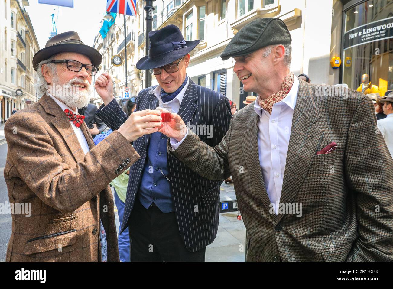 London, UK. 14th May, 2023. Three chaps toast in style kwith rhubarb gin. The annual Grand Flaneur Walk sees chaps and chapettes, dandies and quaintrelle in impeccable tailoring and style flanning and sauntering without purpose around St James' and surrounding areas of London. The walk always starts at the statue of socialite dandy Beau Brummell and slowly makes its way around the area. Credit: Imageplotter/Alamy Live News Stock Photo