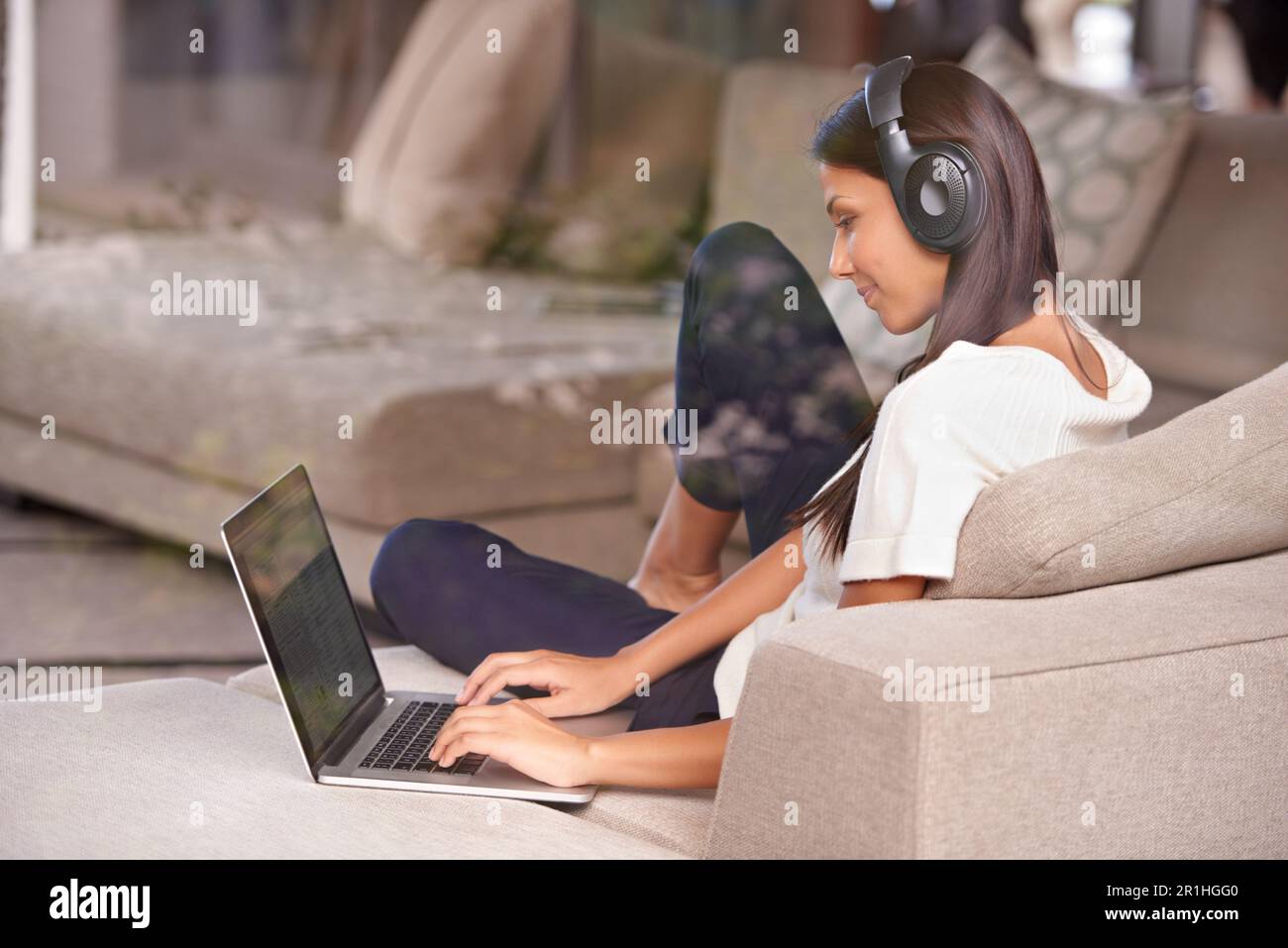 Headphones, typing and woman with laptop on home sofa listening to ...