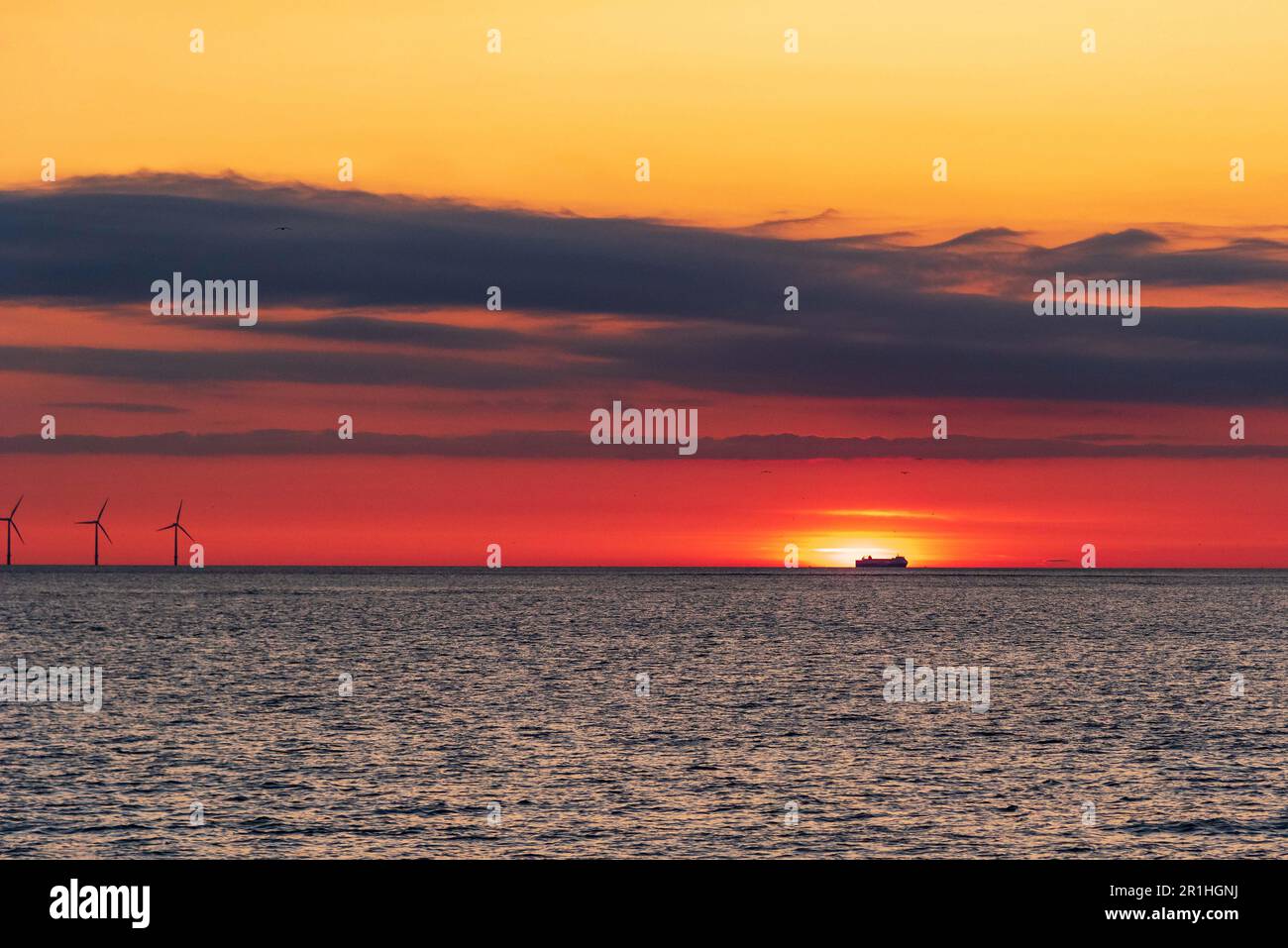 Freight ferry ship on the horizon in sunset across the waves. Stock Photo
