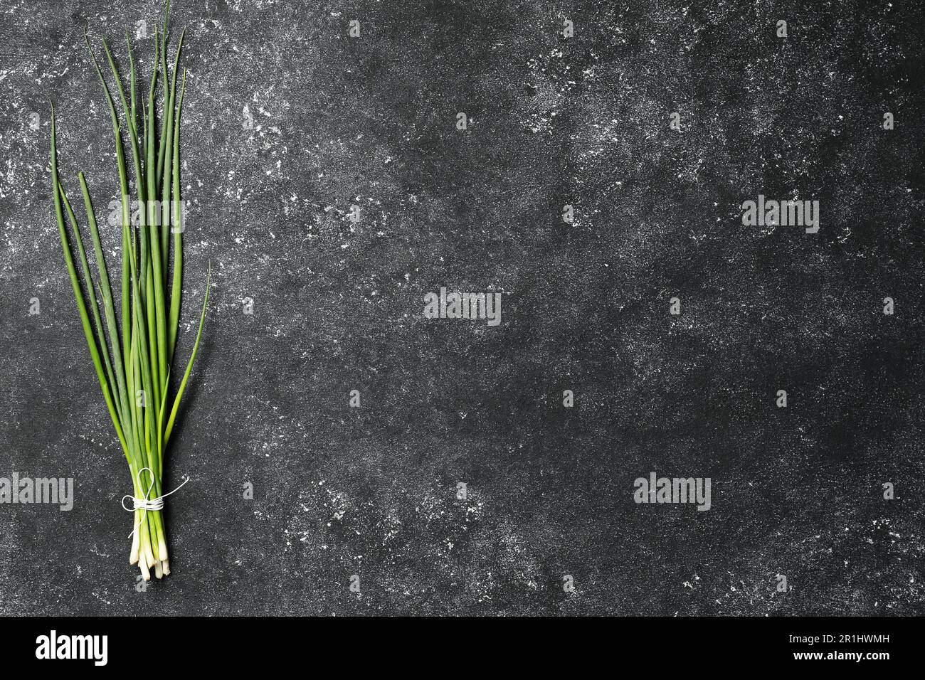 Bunch of fresh green onion on black table, top view. Space for text ...
