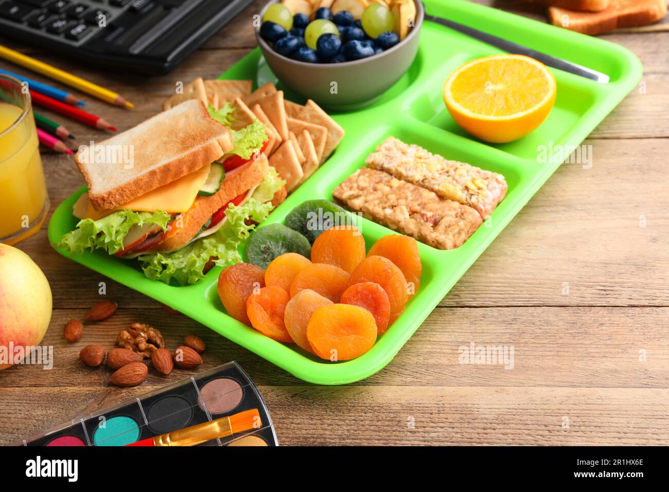 Serving tray of healthy food and stationery on wooden table. School lunch Stock Photo