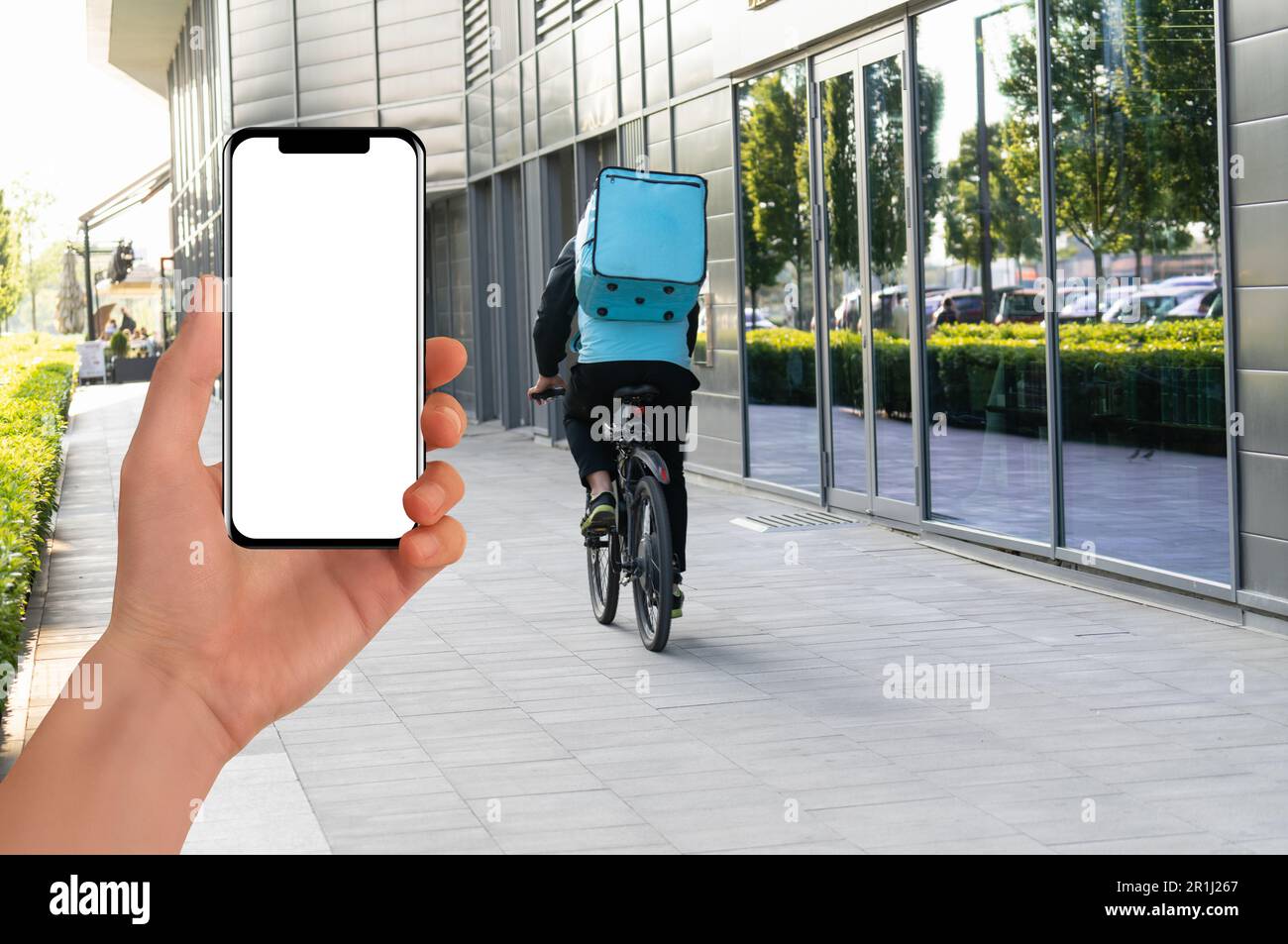 Hand with phone on a background delivery courier on a bike. Mobile application for food delivery. High quality photo Stock Photo