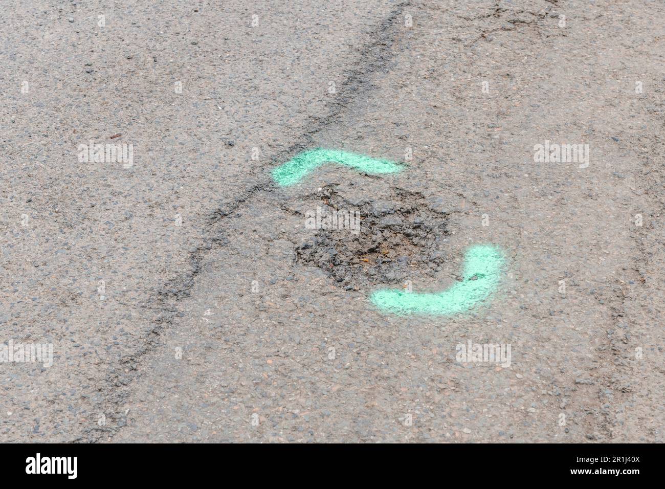 Green spraypainted markings on tarmac surfaced small road. For UK road