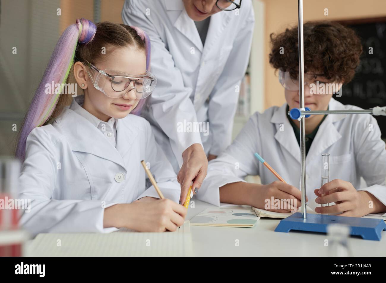 Portrait of cute little schoolgirl with pigtails doing science