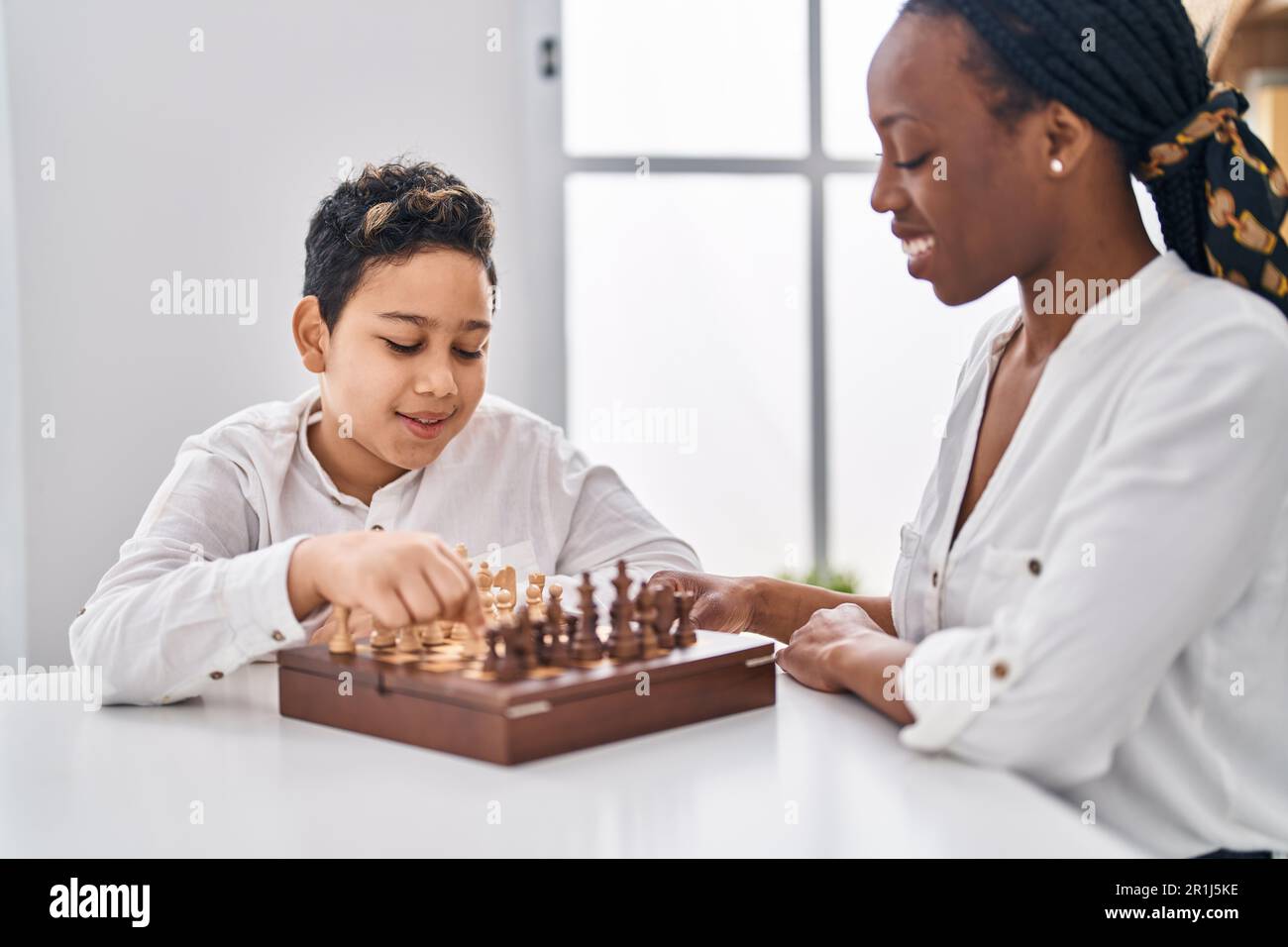 African american mother and son playing chess game sitting on table at home  Stock Photo - Alamy