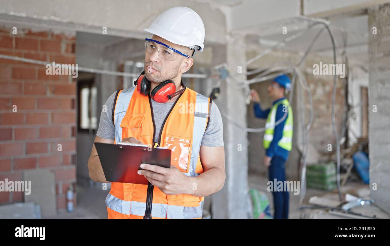 Two men builders writing document working at construction site Stock Photo