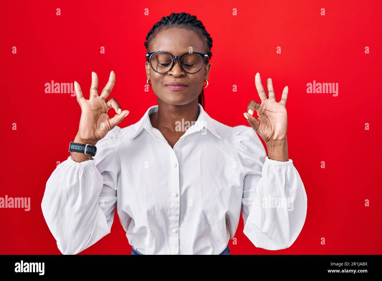 African woman with braids standing over red background relax and ...