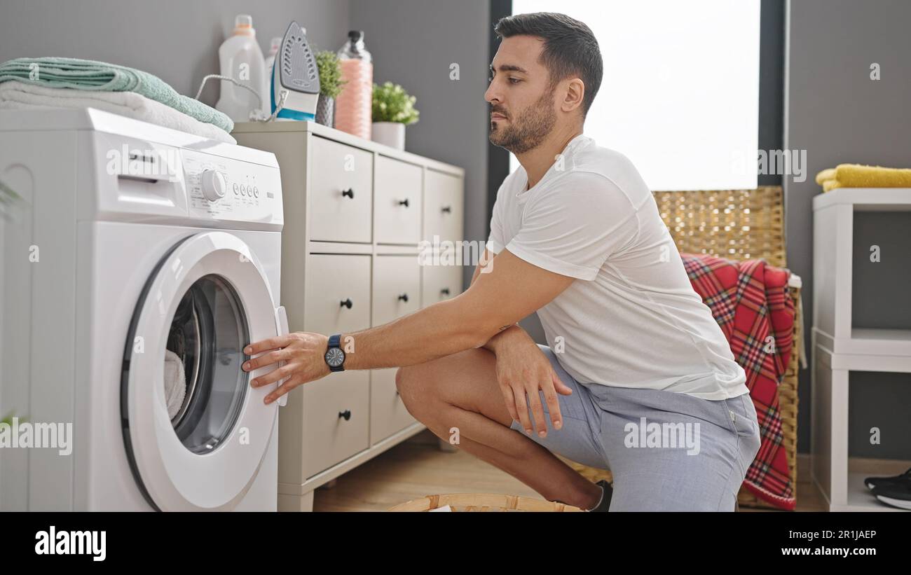 Young hispanic man doing laundry at laundry room Stock Photo