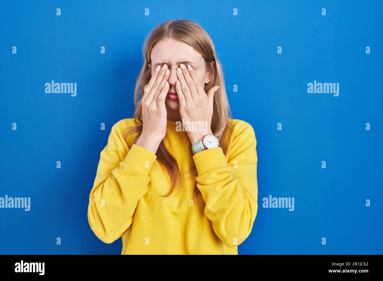Young caucasian woman standing over blue background rubbing eyes for fatigue and headache, sleepy and tired expression. vision problem Stock Photo