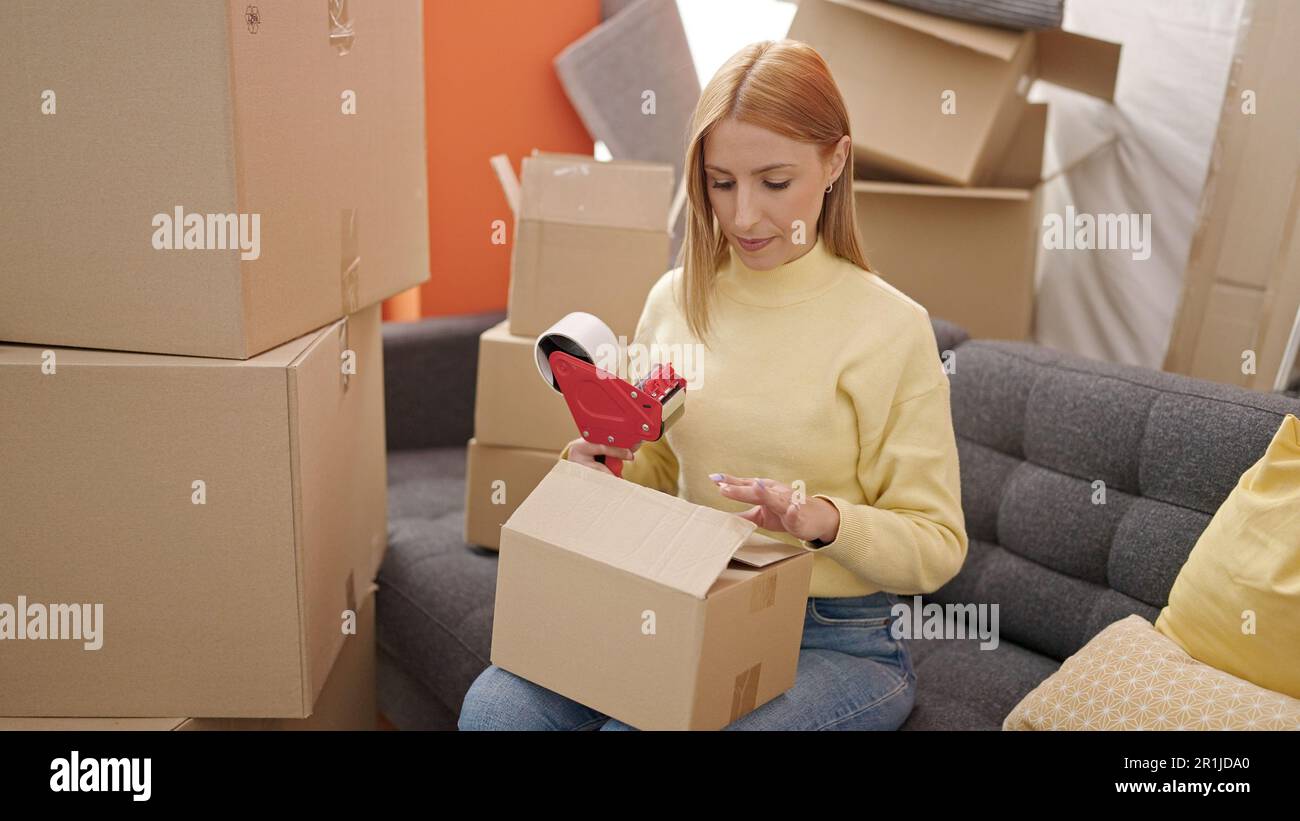 Young blonde woman packing cardboard box at new home Stock Photo - Alamy