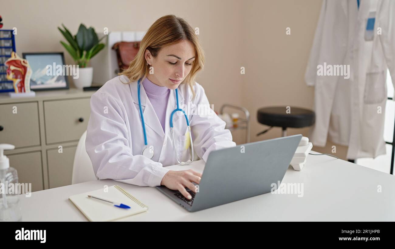 Young beautiful hispanic woman doctor using laptop working at clinic Stock Photo