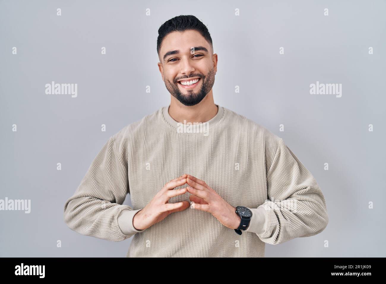 Young handsome man standing over isolated background hands together and ...