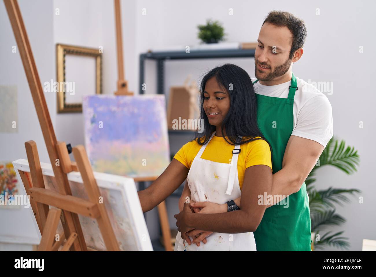 Man and woman artist couple hugging each other drawing at art studio ...