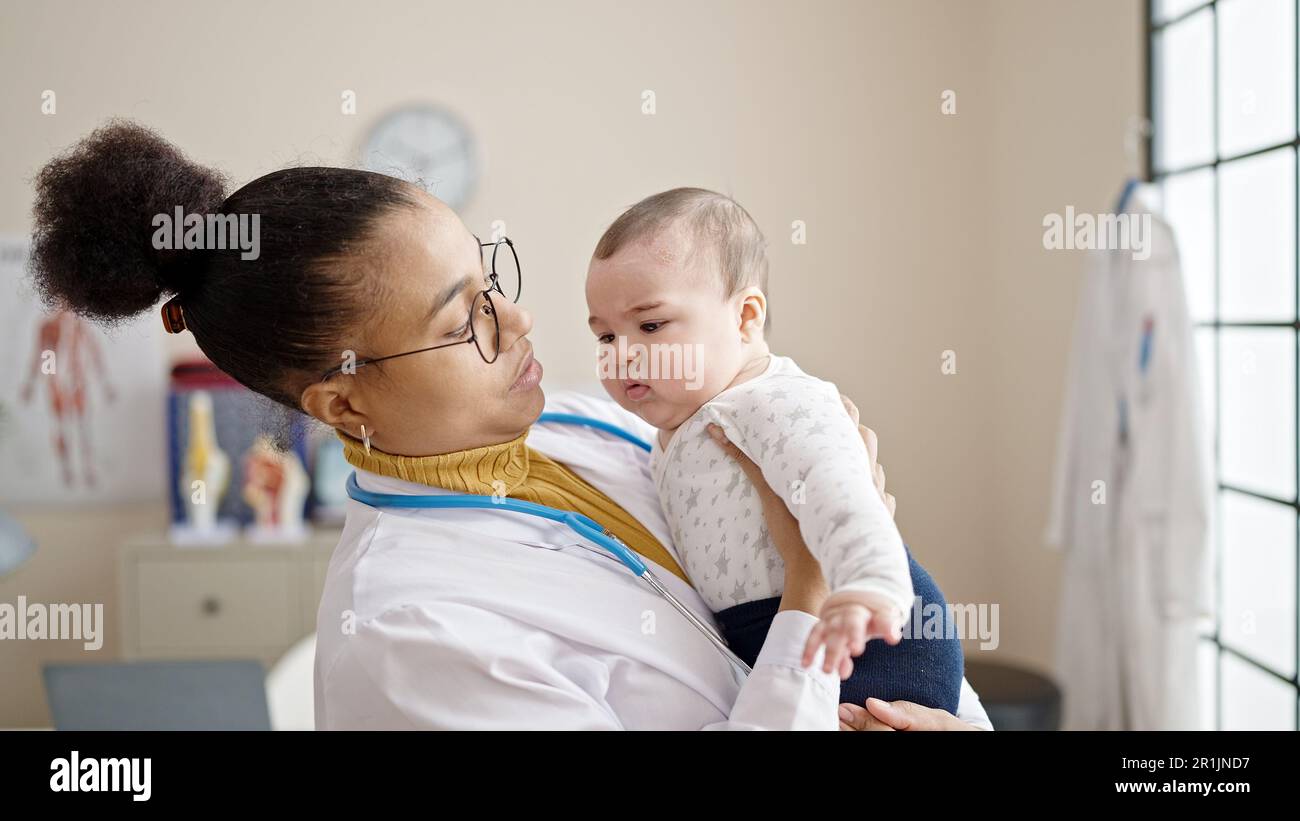 Mother and son doctor holding baby on arms at clinic Stock Photo