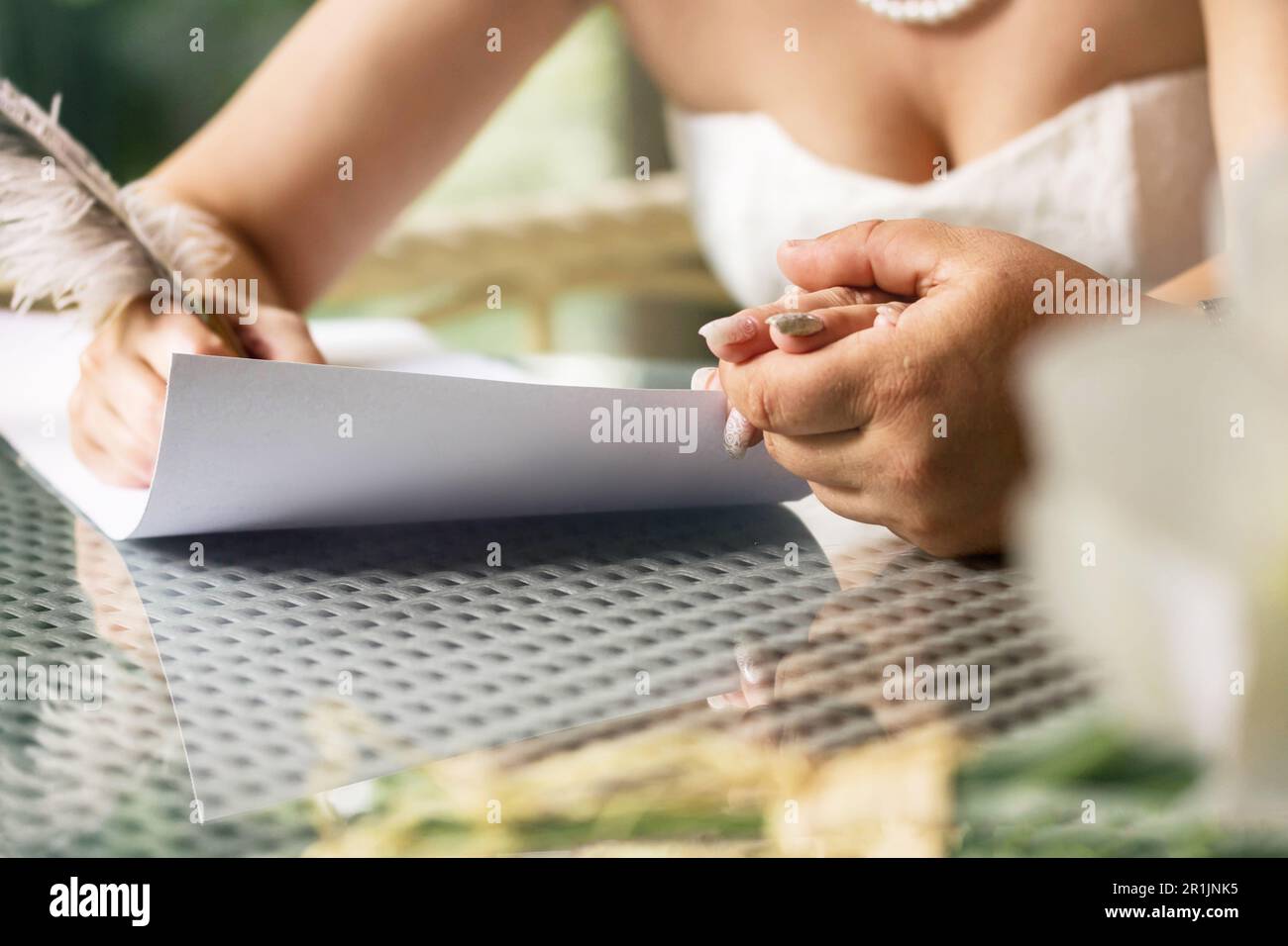 The bride and groom sign a marriage contract. The man holds the woman's hand. Toned image. Stock Photo