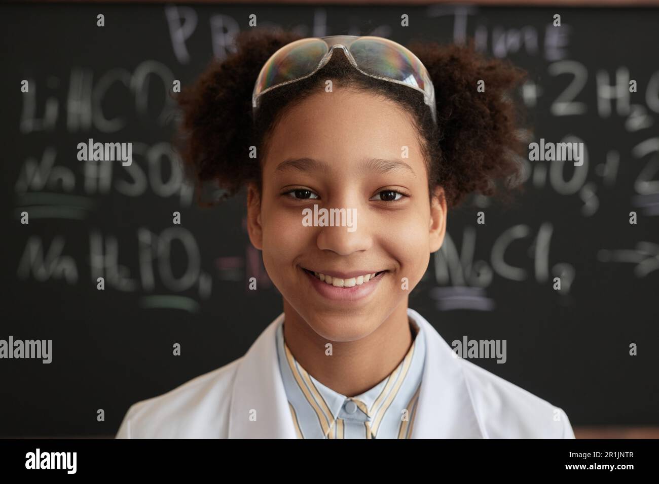 Closeup portrait of smiling black girl wearing lab coat and protective