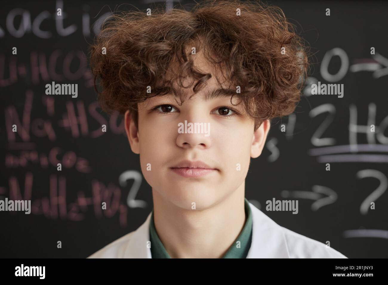 Front view portrait of teenage boy wearing lab coat in science class and looking at camera Stock Photo