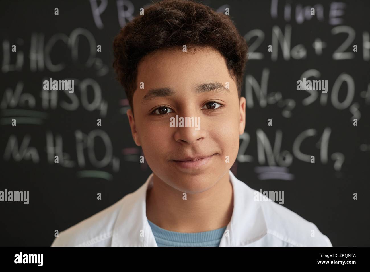 Closeup portrait of multiethnic teen boy wearing lab coat in science