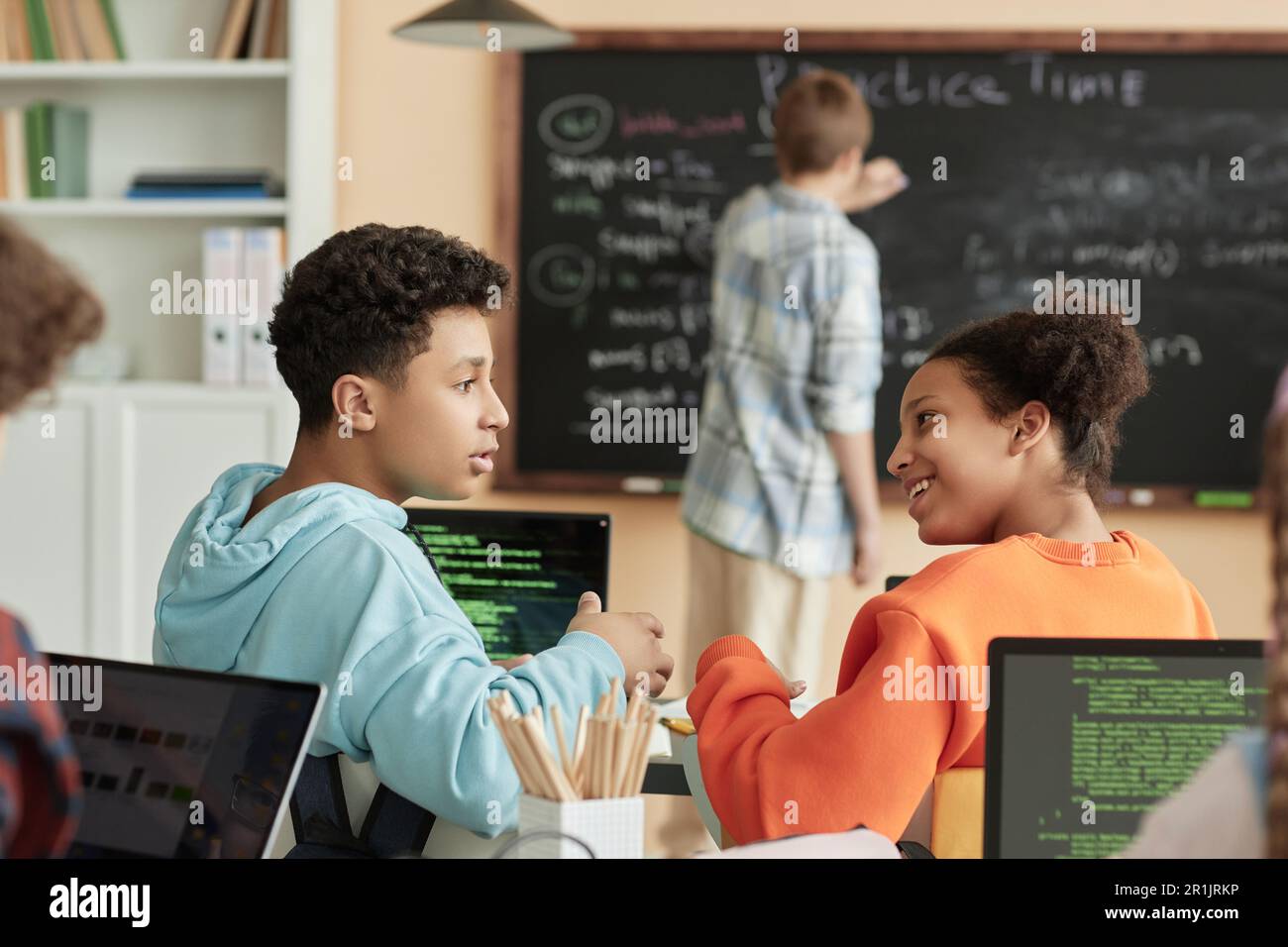 Side view portrait of two teenagers taking in programming class for ...