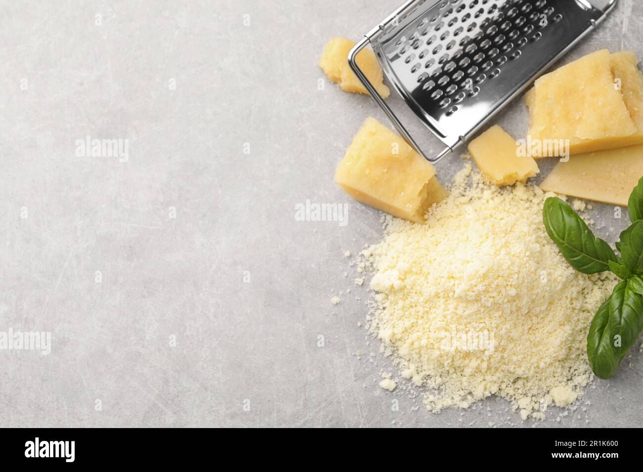 Flat lay composition with grater, basil, parmesan cheese on grey table ...