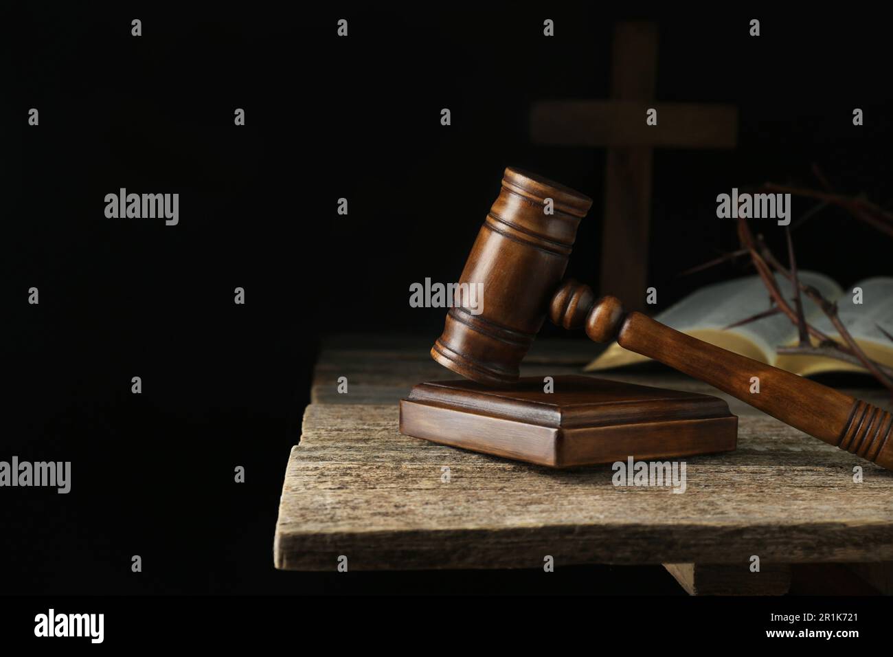 Judge gavel, bible, cross and crown of thorns on wooden table against