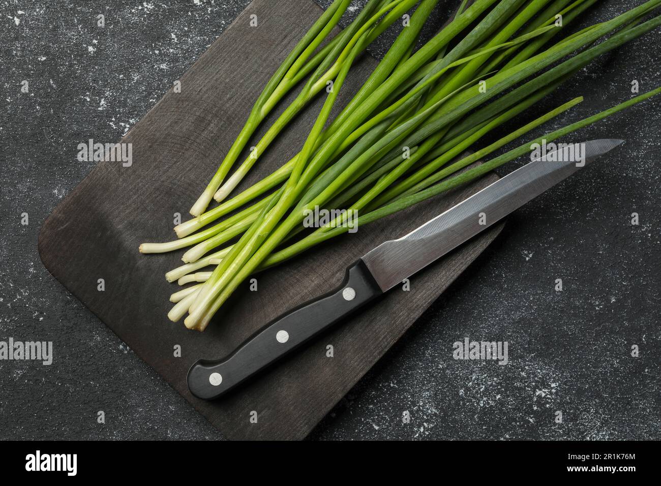 Fresh green onion and knife on black table, top view Stock Photo - Alamy