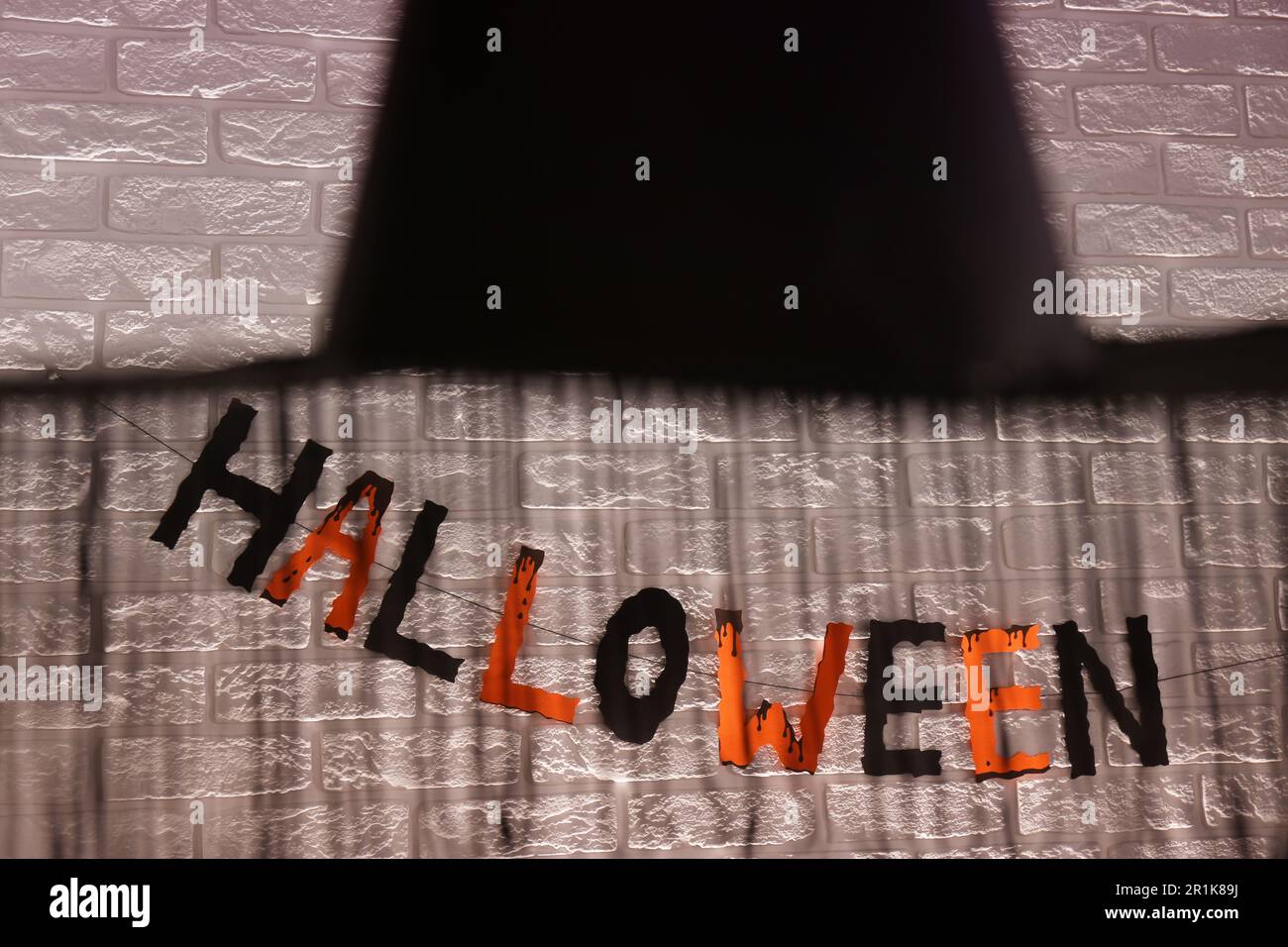 Word Halloween made of colorful letters and festive decor on brick wall Stock Photo