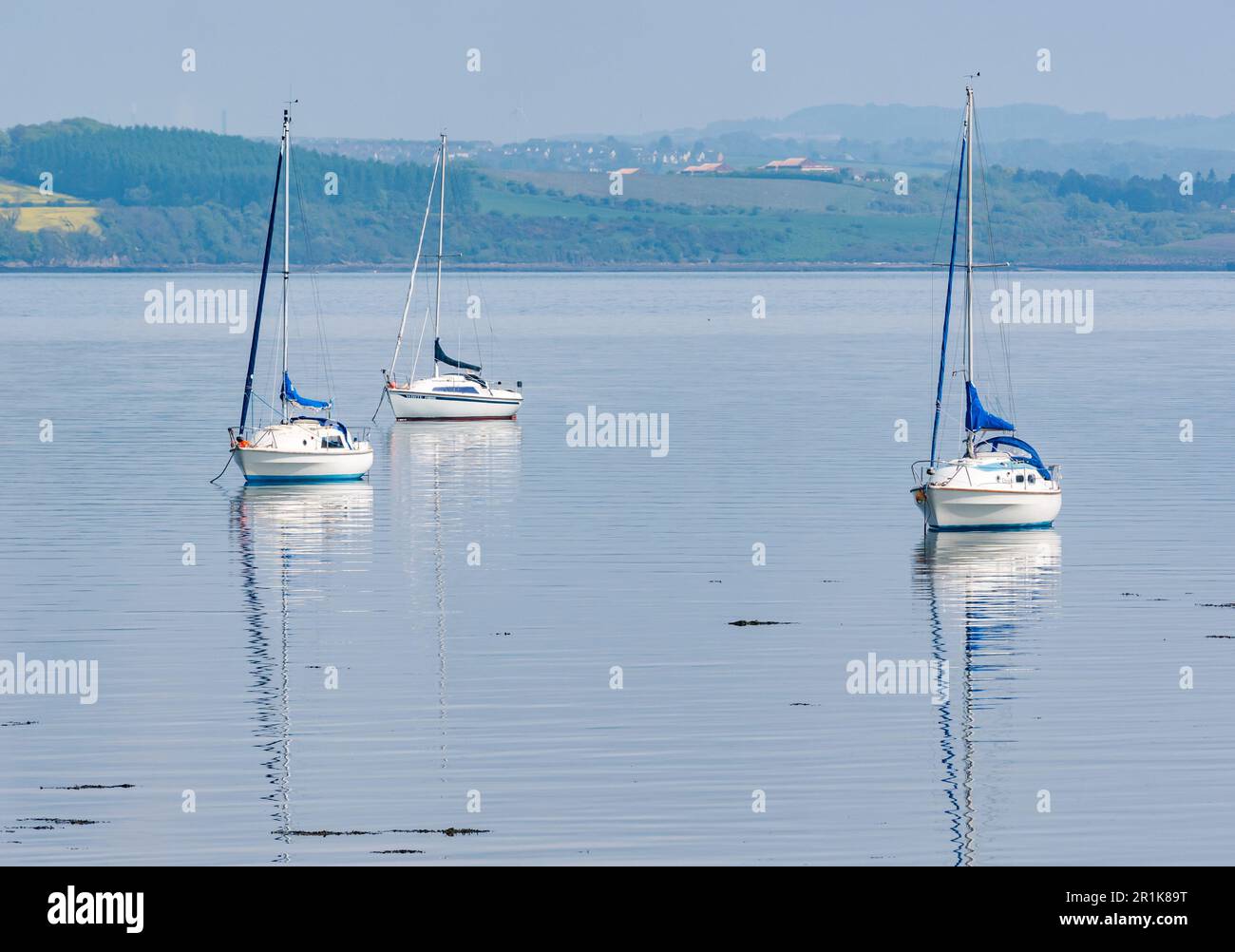 Moored sailing boats in calm water on hazy sunny day, Firth of Forth, Scotland, UK Stock Photo