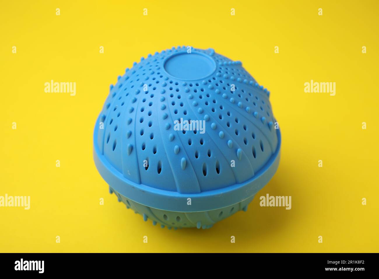 Dryer ball for washing machine on yellow background. Laundry detergent
