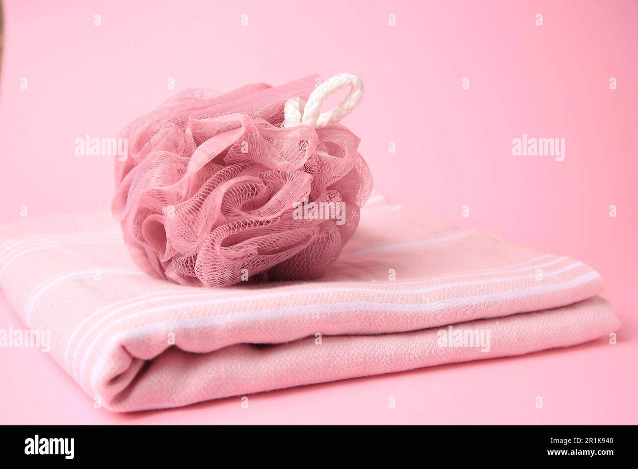Shower puff with towel on pink background Stock Photo - Alamy