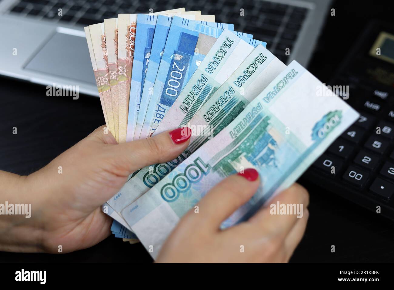 Russian rubles in hands of woman on laptop and calculator background. Wages in Russia, bonus or bribe concept Stock Photo