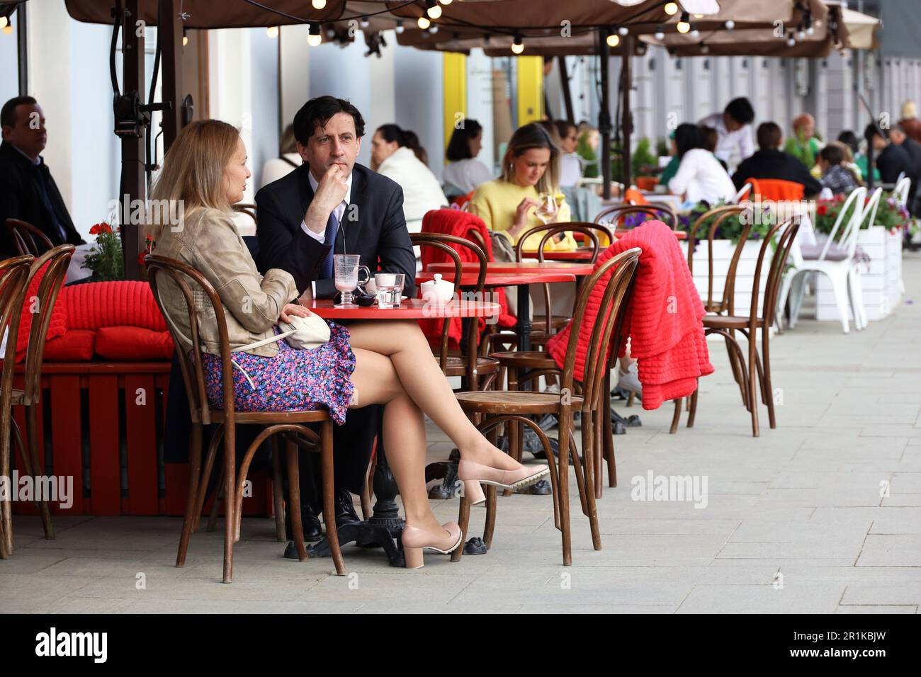 People eating in street cafe, couple sitting in foreground. Life and leisure in spring city Stock Photo