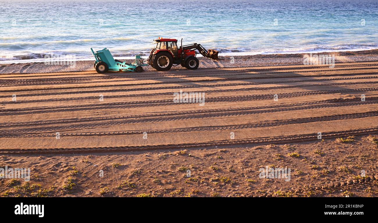 Tractor with trailer for cleaning the beach from winter debris. The ...