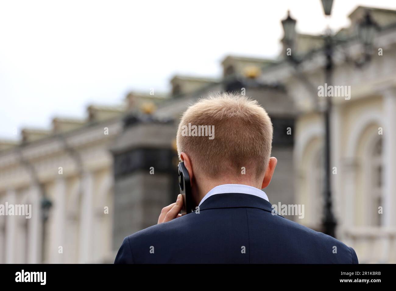 Short haired man in a business suit talking on mobile phone on a city street. Concept of cellular communication Stock Photo