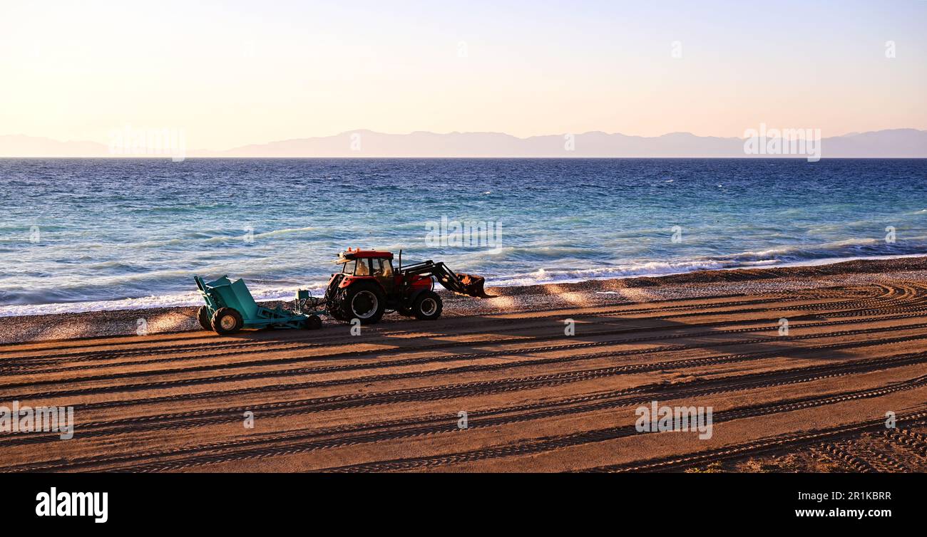 Tractor with trailer for cleaning the beach from winter debris. The ...