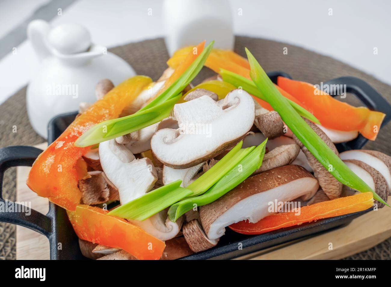 Shiitake mushrooms with frozen vegetables, bell peppers, onions and tomatoes are ready for cooking. Vegetable vegetarian dish with shiitake mushrooms. Stock Photo