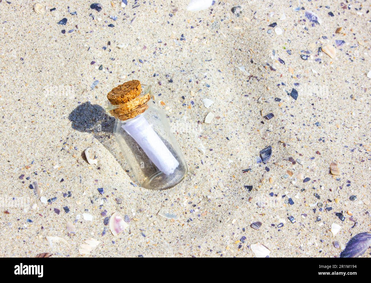 A message in a Corked Bottle on a beach. The bottle in the sand. The bottle on sandy beach. Sunny day. Stock Photo