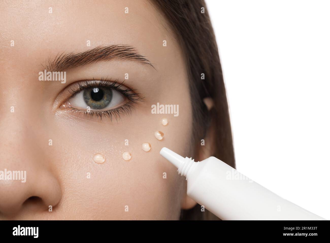 Young woman applying cream under eye on white background, closeup Stock Photo