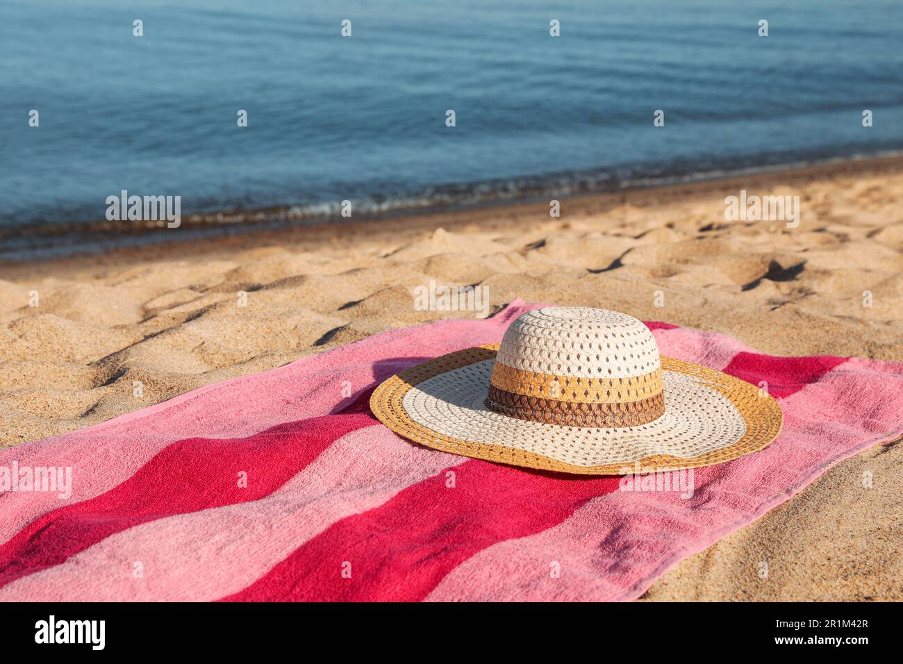 Beach towel and straw hat on sand near sea Stock Photo - Alamy