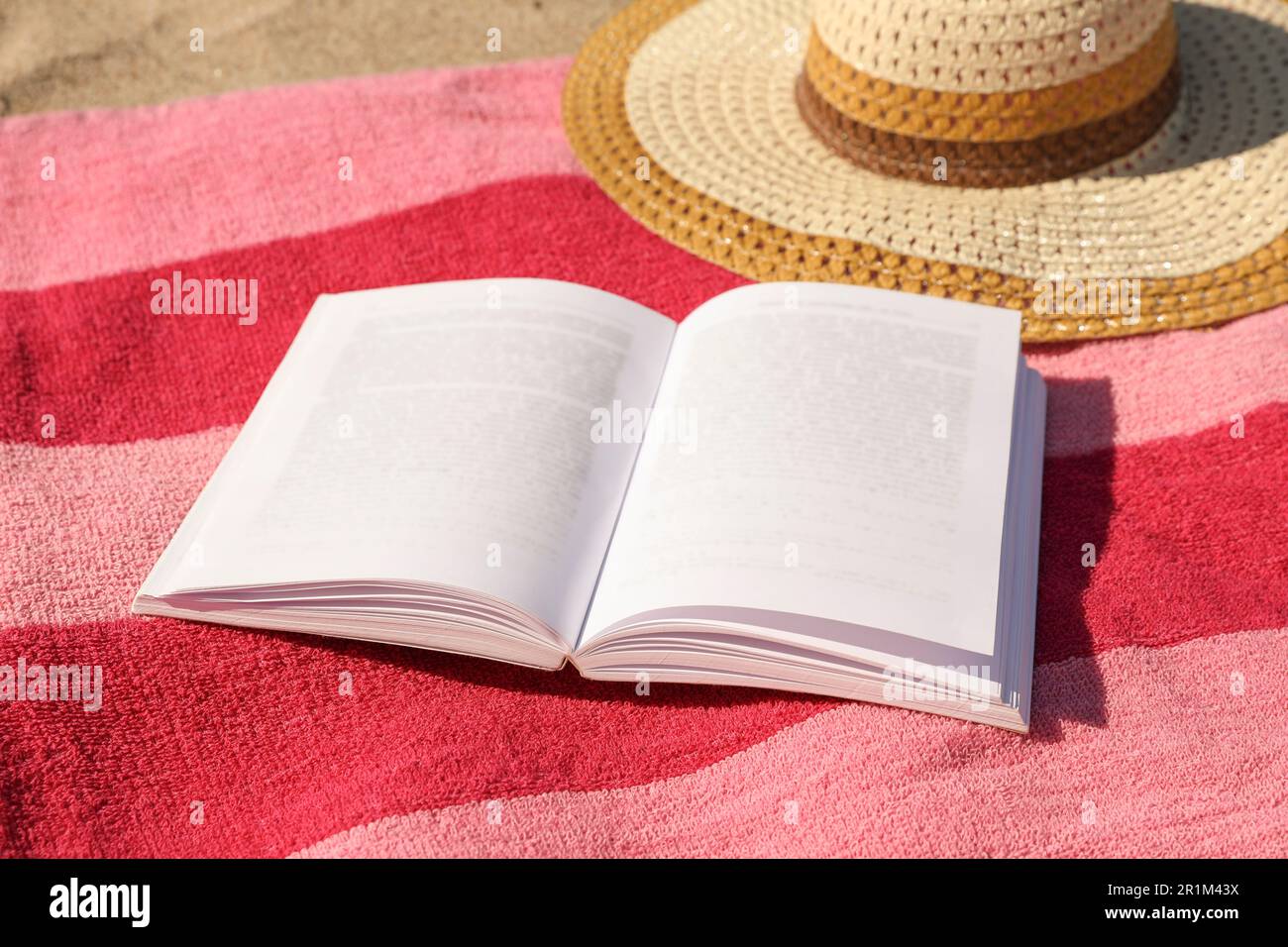 Open book, hat and striped towel on sandy beach Stock Photo - Alamy