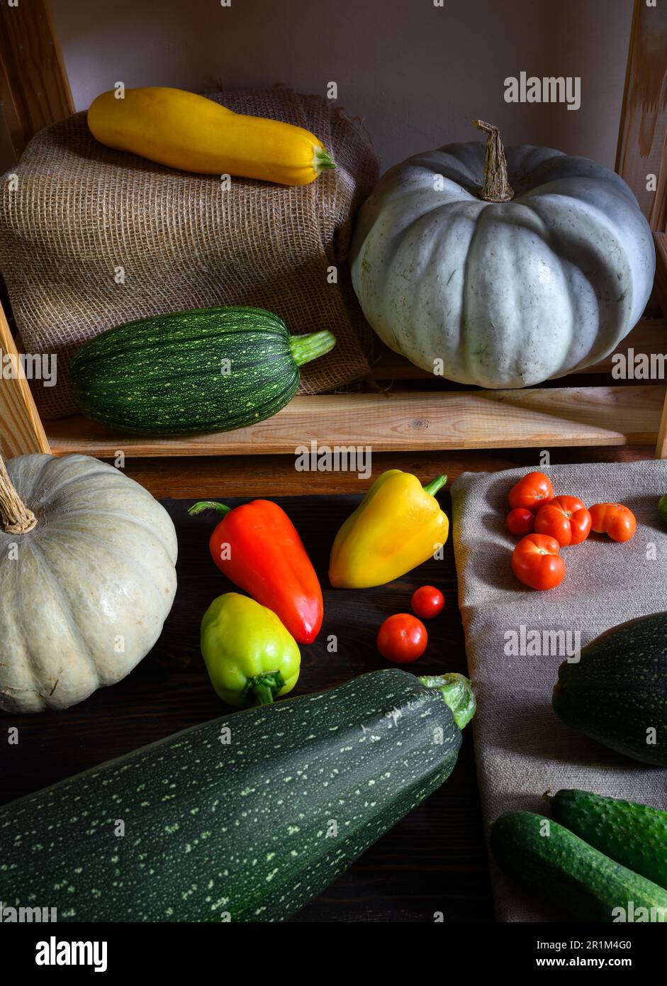Vegetable marrow and pumpkins on wooden shelves at home, still life of organic food. Zucchini, sweet pepper and tomatoes in rustic interior. Harvest, Stock Photo