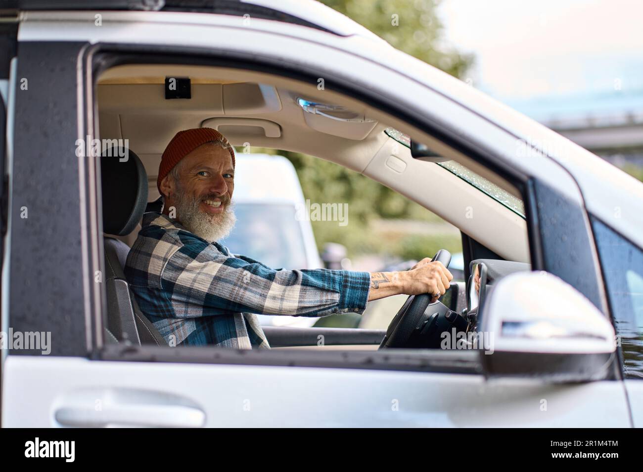 Happy older man driving camper van sitting inside, campervan rentals. Stock Photo