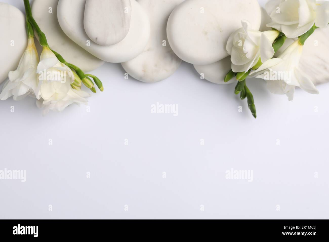 Flat lay composition with spa stones and freesia flowers on white ...