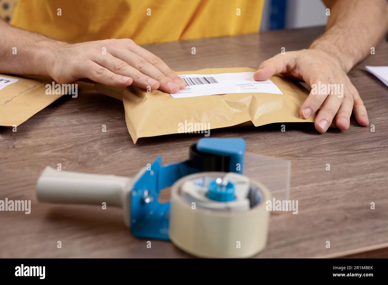 Post office worker sticking barcode on parcel at counter indoors ...