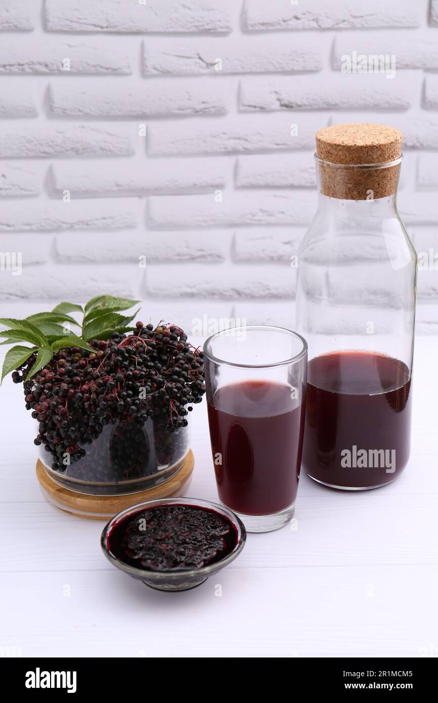 Elderberry drink and jam with Sambucus berries on white wooden table, space  for text Stock Photo - Alamy