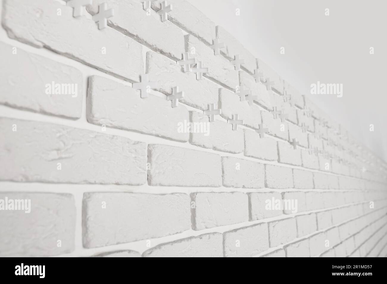Decorative white bricks with tile leveling system on wall Stock Photo