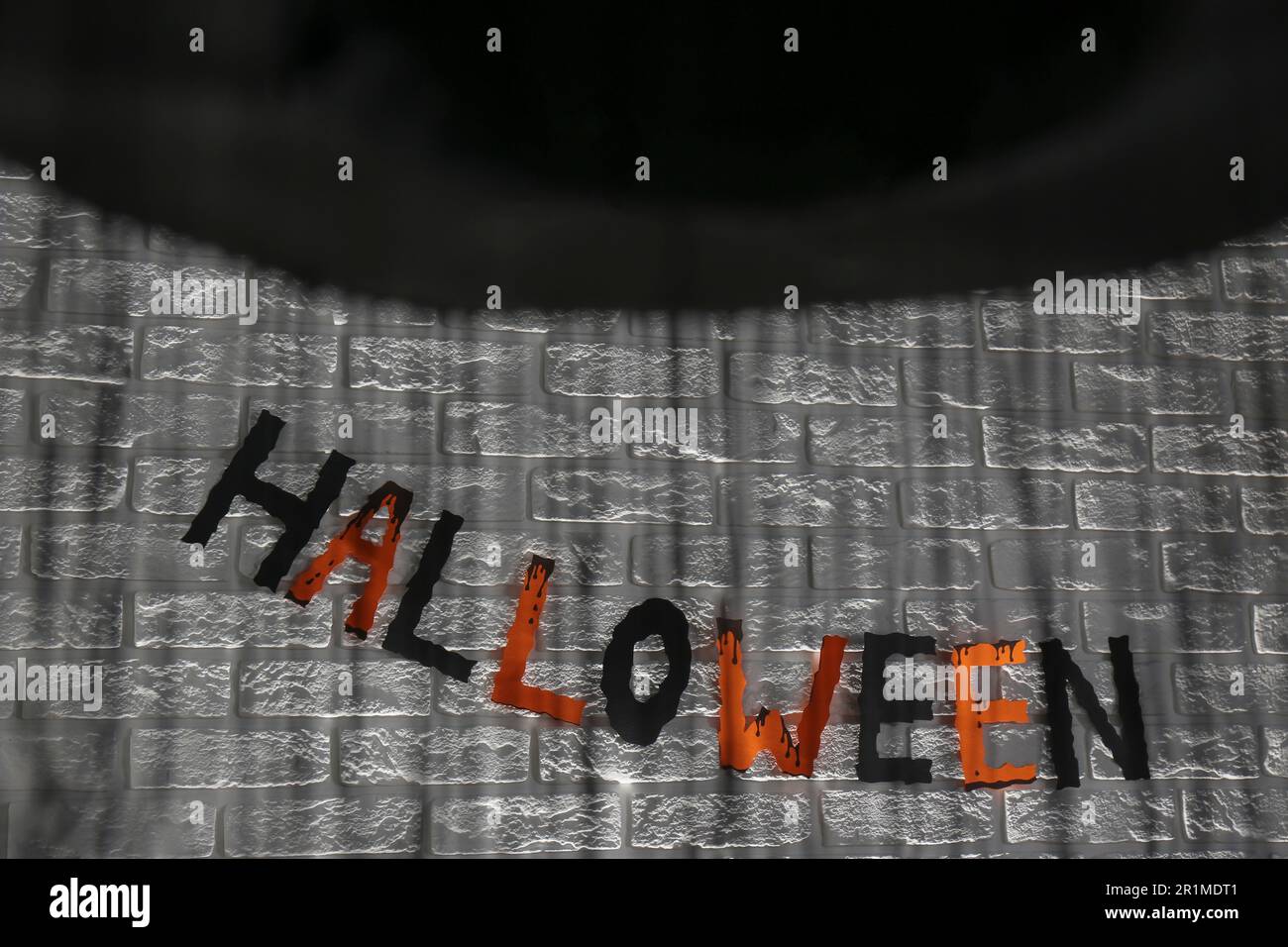 Word Halloween made of colorful letters and festive decor on brick wall Stock Photo